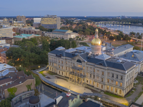 The capital statehouse of New Jersey lights up as the sun sets the Delaware River in the background city of Trenton