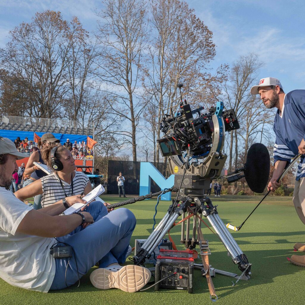 Adam Sandler poses with a golf club filming a