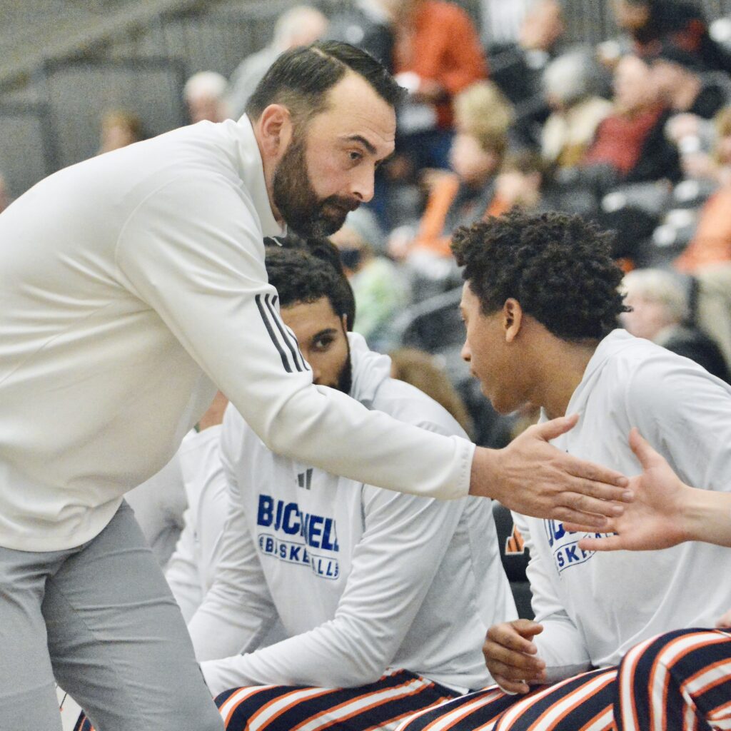 Bucknell coach John Griffin III slaps hands with a player...