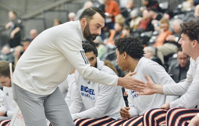Bucknell coach John Griffin III slaps hands with a player...